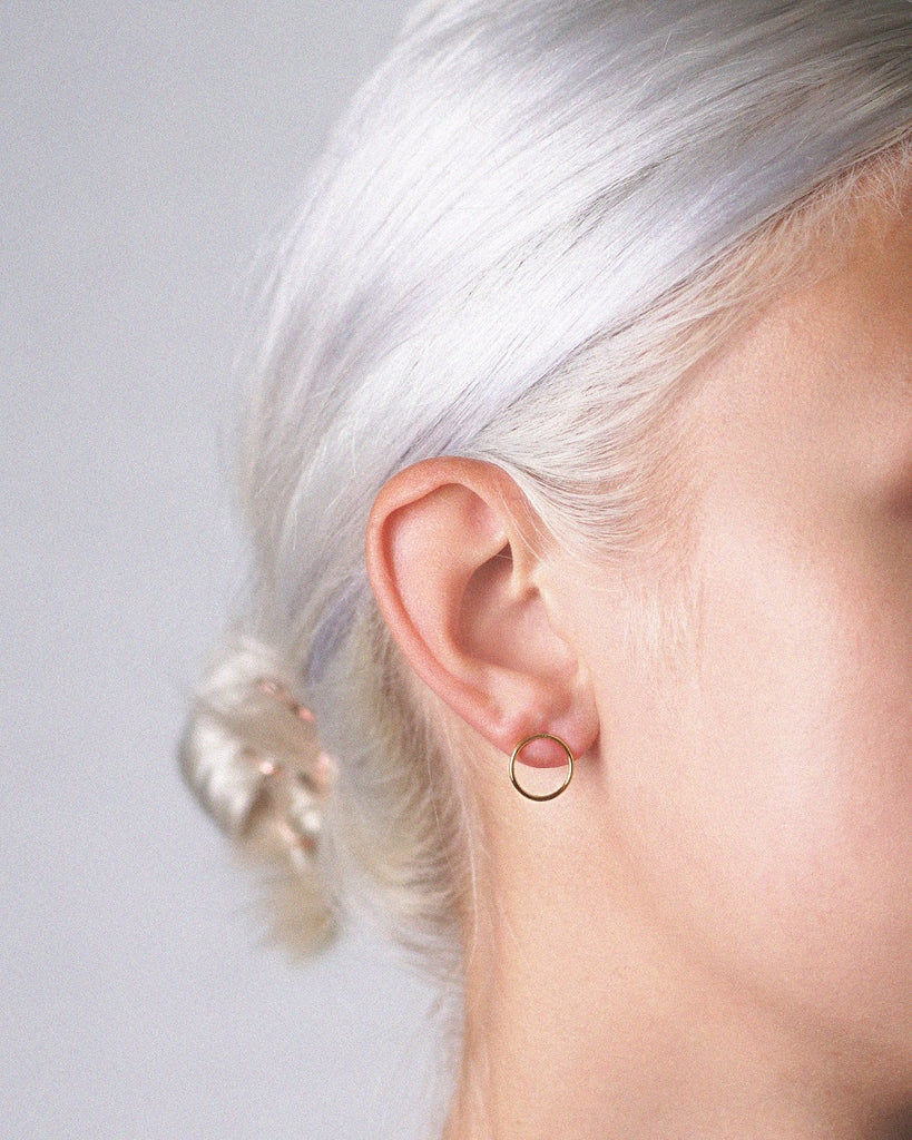 Model wearing tiny gold vermeil Cici circle stud earrings - featuring delicate circular design in high-quality sterling silver and 24k gold.
