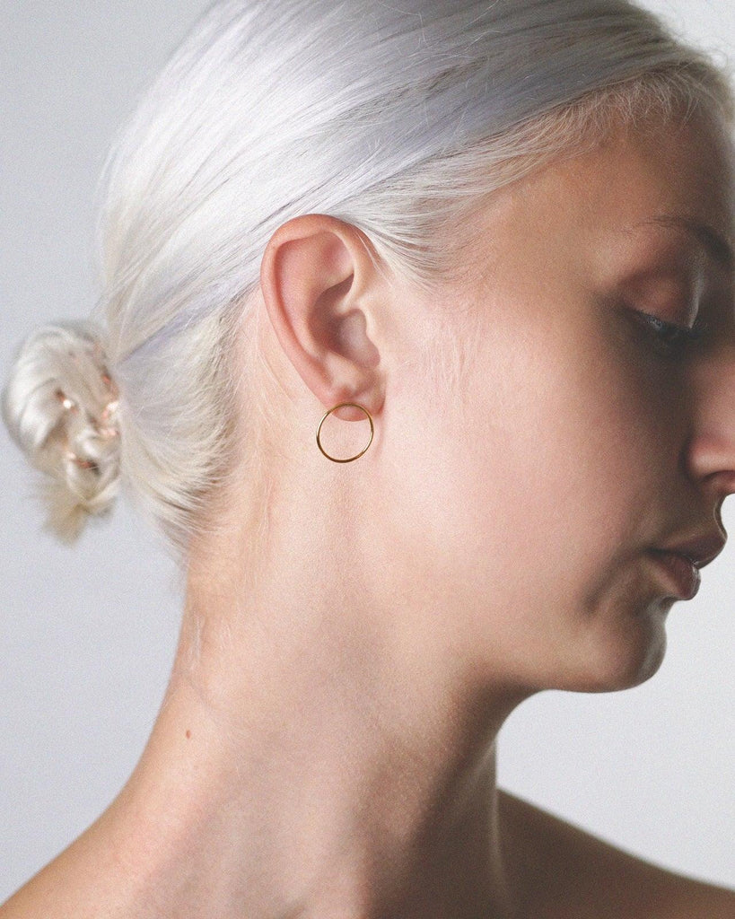 Model showcasing the stunning gold vermeil medium hoop earring studs for a fashionable and chic appearance.