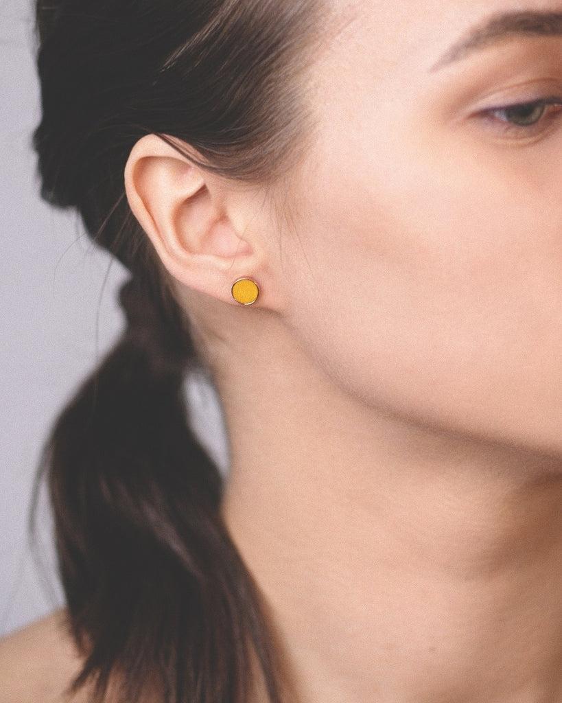 Model wearing Cosmic earrings - Handcrafted birch wood and sterling silver studs with a  sol yellow birch wood interior, plated with 24k gold.