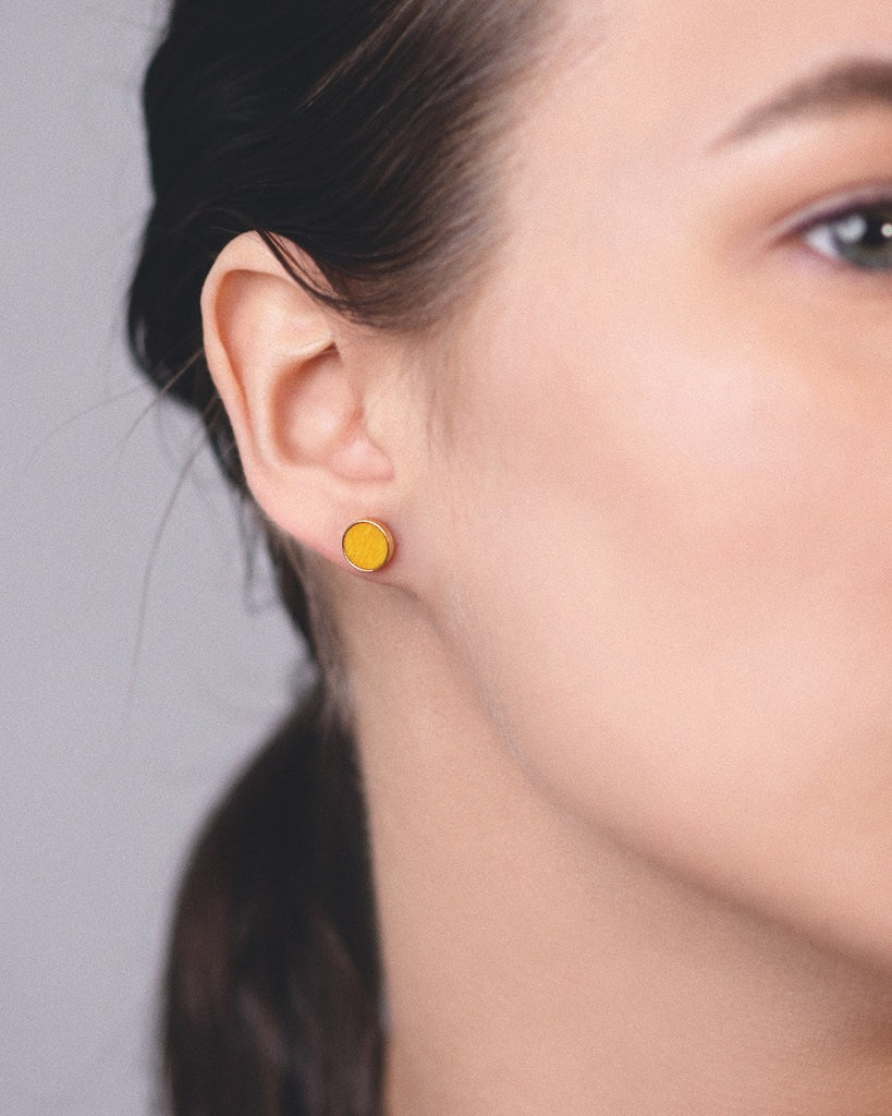 Model wearing Cosmic earrings - Handcrafted birch wood and sterling silver studs with a  sol yellow birch wood interior, plated with 18k rose gold.