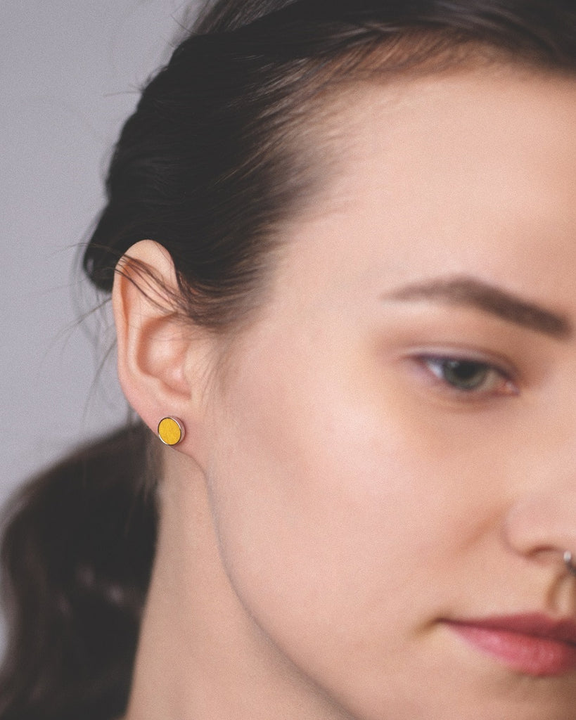 Model wearing Cosmic earrings - Handcrafted birch wood and sterling silver studs with a  sol yellow birch wood interior, plated with platinum.