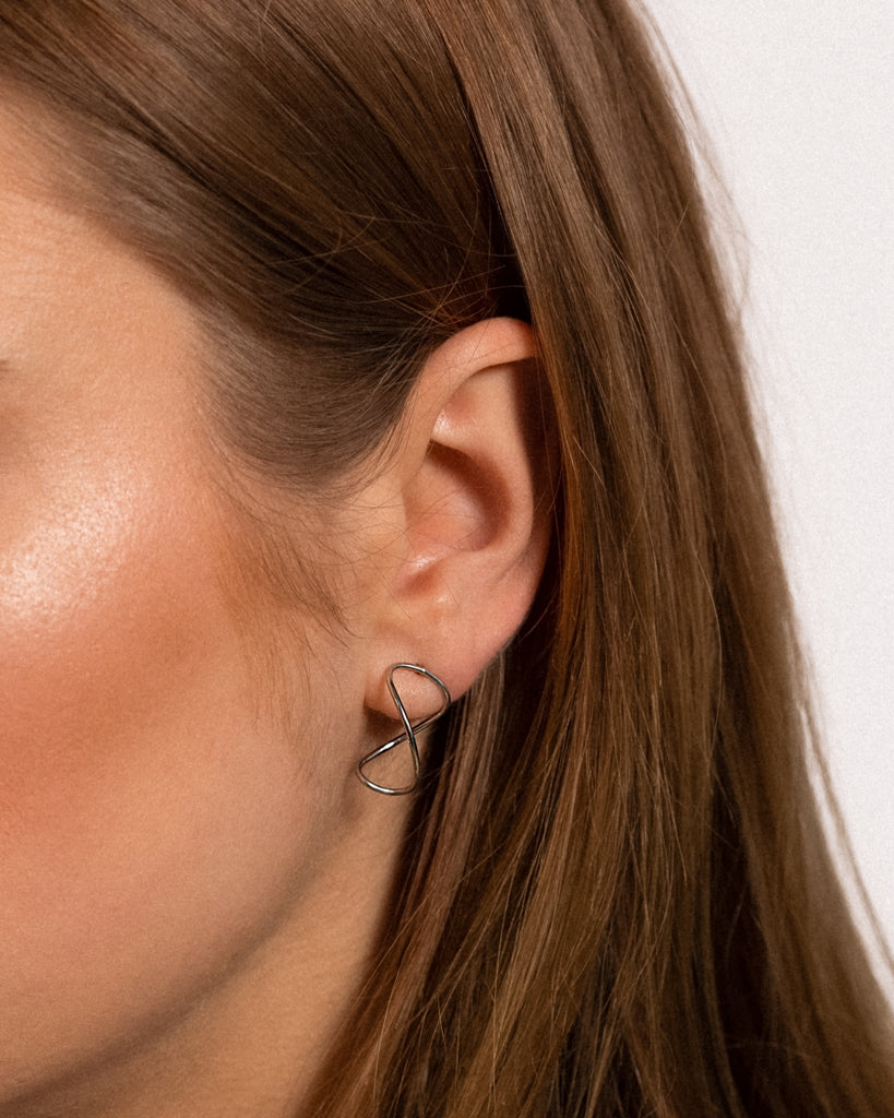 Modell kannab Curl Infinity hõbe Kõrvarõngaid, kaetud plaatinaga.