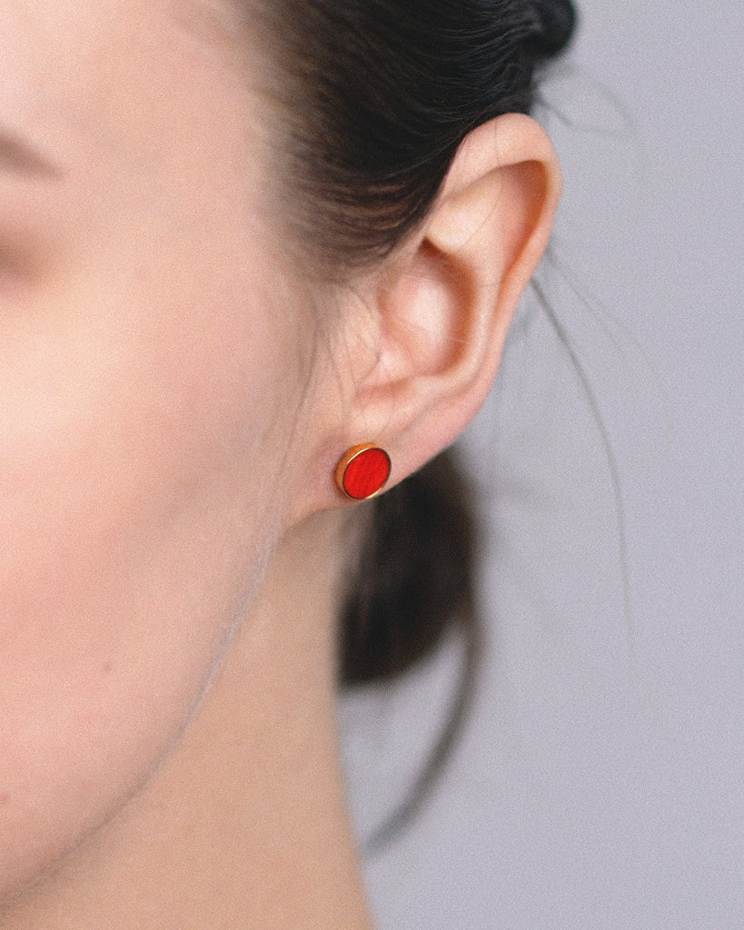 Model wearing Cosmic earrings - Handcrafted birch wood and sterling silver studs with a  distant red birch wood interior, plated with 24k gold.