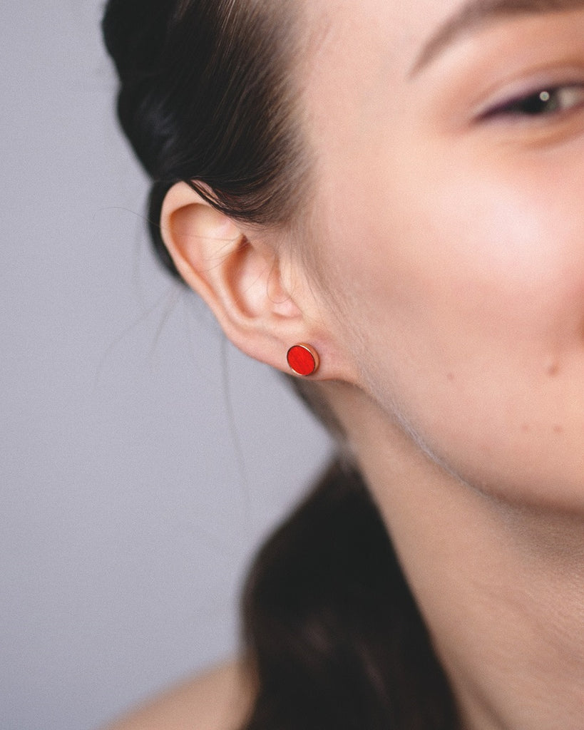 Model wearing Cosmic earrings - Handcrafted birch wood and sterling silver studs with a  distant red birch wood interior, plated with 18k rose gold.