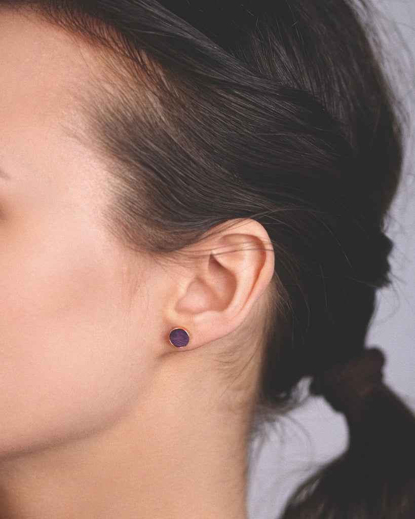 Model wearing Cosmic earrings - Handcrafted birch wood and sterling silver studs with a  orion purple birch wood interior, plated with 18k rose gold.