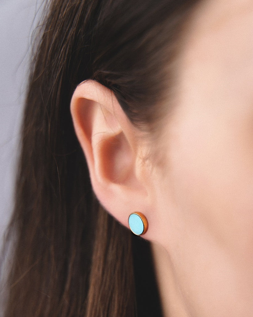 Model wearing Cosmic earrings - Handcrafted birch wood and sterling silver studs with a  magnetar blue birch wood interior, plated with 24k gold.