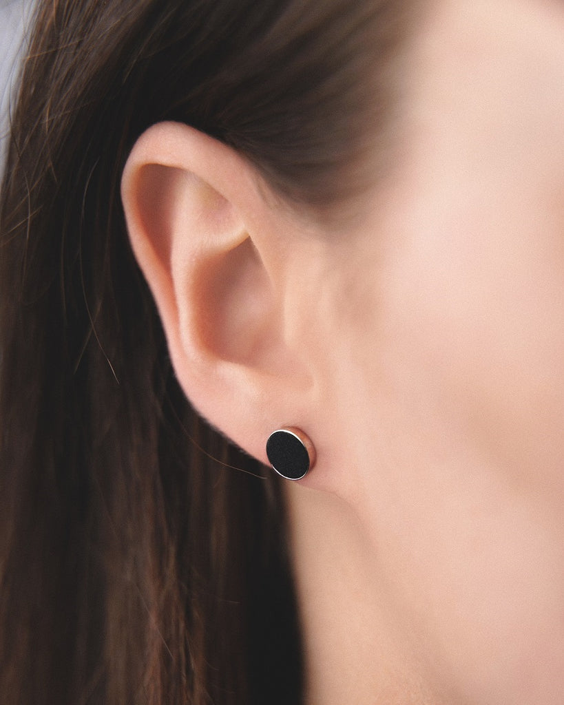 Model wearing Cosmic earrings - Handcrafted birch wood and sterling silver studs with a  gravity black birch wood interior, plated with platinum.