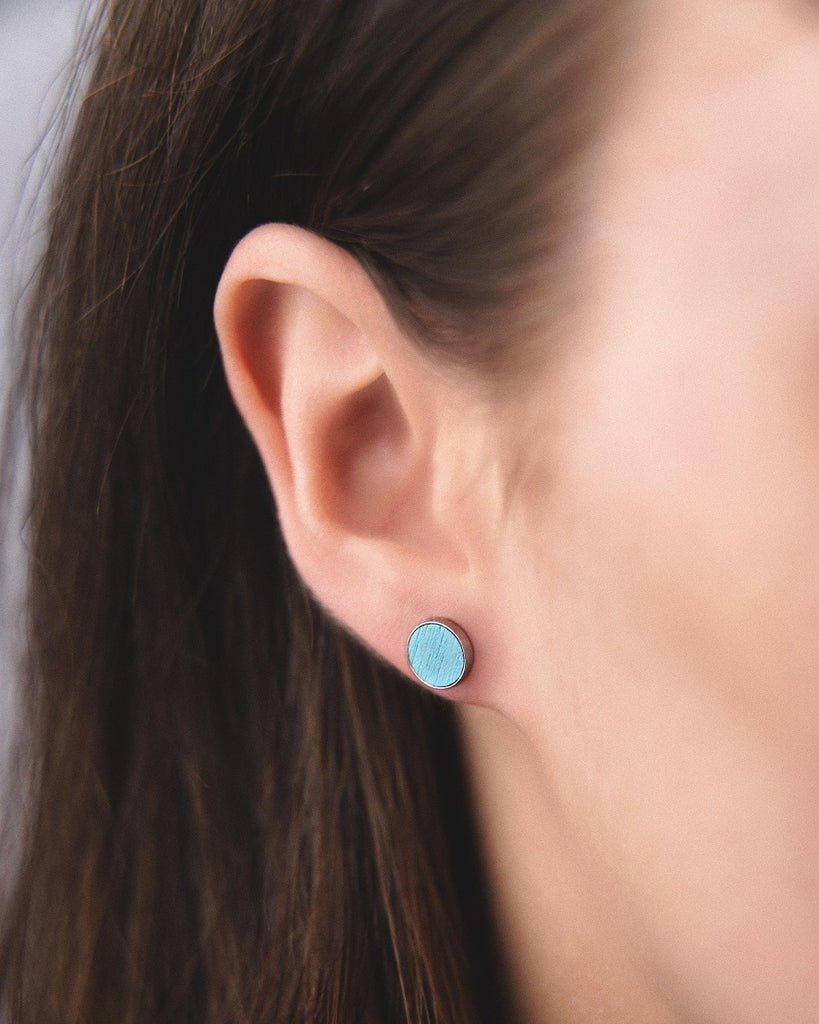 Model wearing Cosmic earrings - Handcrafted birch wood and sterling silver studs with a  magnetar blue birch wood interior, plated with platinum.