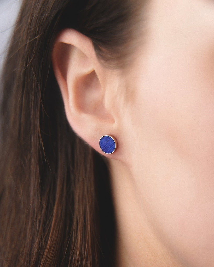 Model wearing Cosmic earrings - Handcrafted birch wood and sterling silver studs with a ocean blue birch wood interior, plated with platinum.