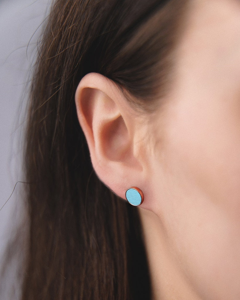 Model wearing Cosmic earrings - Handcrafted birch wood and sterling silver studs with a  magnetar blue birch wood interior, plated with 18k rose gold.