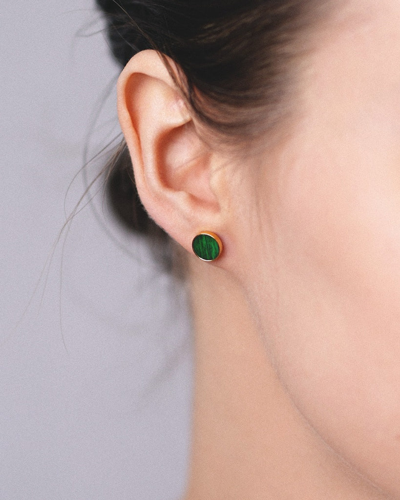 Model wearing Cosmic earrings - Handcrafted birch wood and sterling silver studs with a  aurora green birch wood interior, plated with 24k gold.